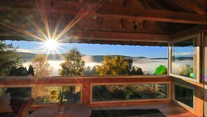 A wooden deck with a view of a sunrise over a misty landscape. - Holiday Home Scharzwald (Feldberg)