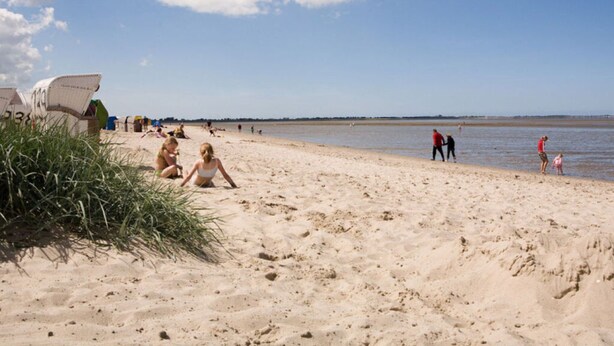 A beach with people relaxing and walking along the shore. - Holiday Apartment Gerdes (Wangerland)