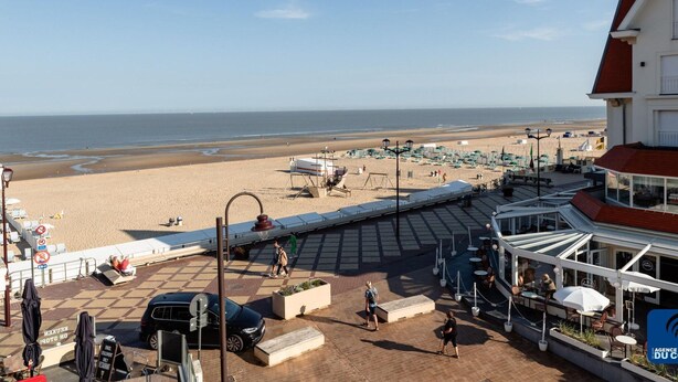 Un hotel frente al mar con terraza al aire libre y vistas a la playa.