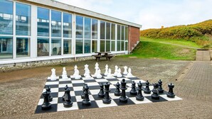 A chessboard set up on a paved area in front of a building with large windows. - 8 Person Holiday Park Home in Ringkobing (Ringkobing)