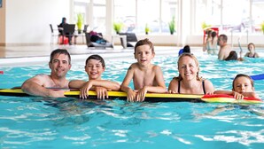 An indoor swimming pool with clear water, a lifeguard chair, and a few people in the background. - 8 Person Holiday Park Home in Ringkobing (Ringkobing)