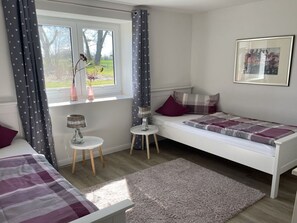 A bedroom with a single bed, a small table, a lamp, and a window with curtains. - Spacious Apartment With Balcony (Kronsgaard)