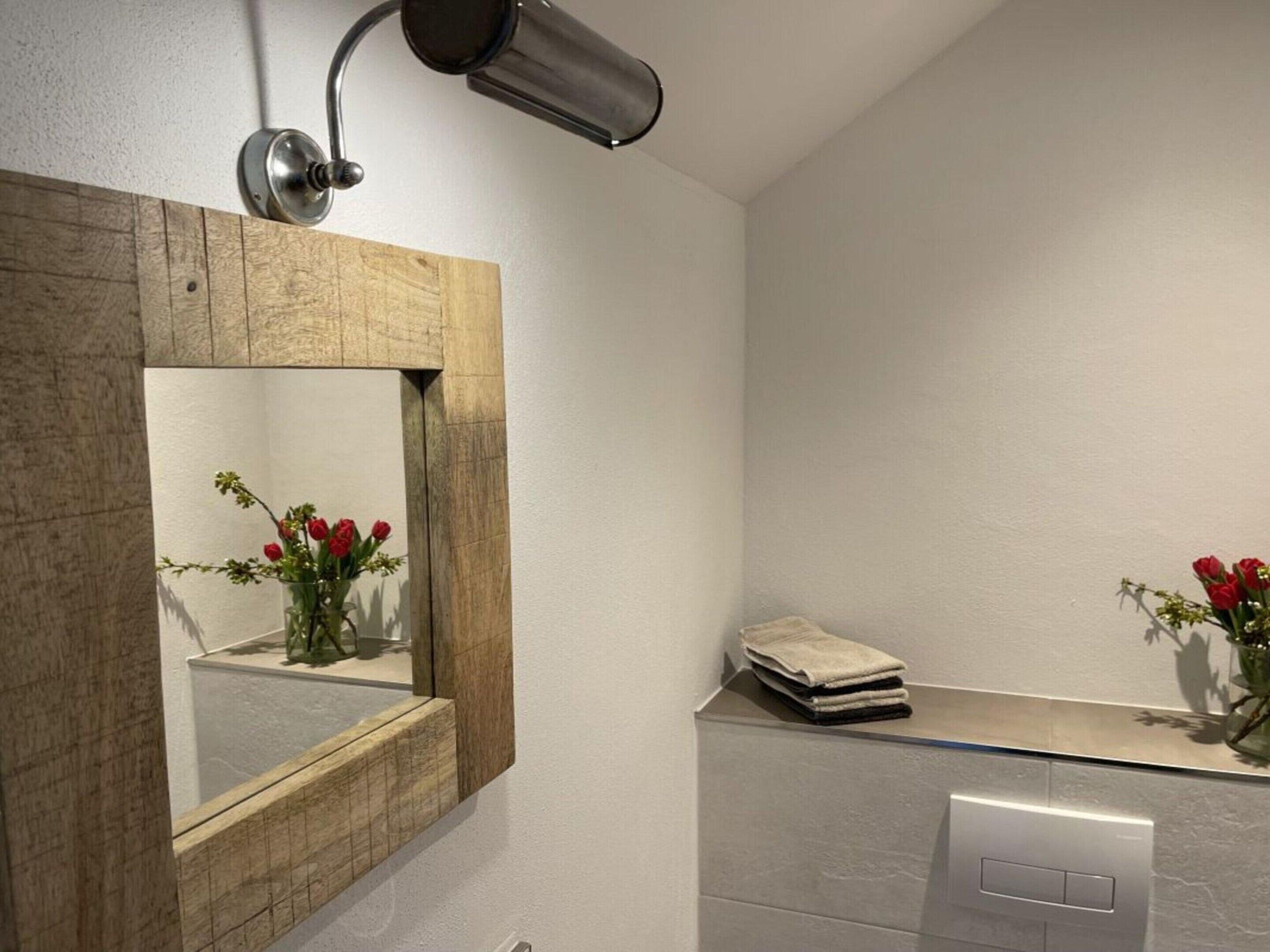 A bathroom with a wooden-framed mirror, a towel rack, and a sink with a modern faucet.