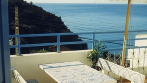 Una terraza con mesa y bancos, con vistas al mar.