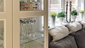 Ein Zimmer mit einer Glasvitrine, die verschiedene Gläser zeigt, und einem Sofa mit Kissen.