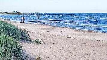A sandy beach with waves and a lifeguard stand.