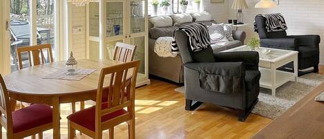 A spacious living area with a dining table, chairs, a sofa, and a coffee table.