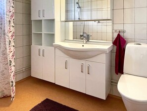 A bathroom with a white sink, mirror, and toilet. There is a shower visible in the background. - 4 Star Holiday Home in Farjestaden (Farjestaden)