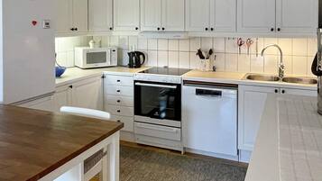 A compact kitchen with white cabinetry, a microwave, an oven, and a dishwasher.