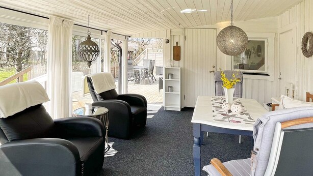 Ein modernes Interieur mit Essbereich, zwei schwarzen Ledersofas, einem kleinen Tisch und einer Pendelleuchte.