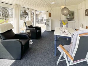 A modern interior with a dining area, two black leather sofas, a small table, and a hanging light fixture. - 4 Star Holiday Home in Farjestaden (Farjestaden)