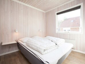 A bedroom with a bed, wooden walls, a window, and two wall-mounted lights. - 6 Person Holiday Park Home in Blavand (Blavand)