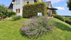 A two-story house with a well-maintained lawn and a large bush in the front yard. - "moseltor" Comfortable Holiday Residence (Monzelfeld)