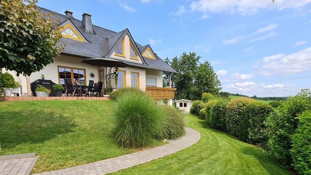 A two-story house with a paved driveway leading to a patio area. - "moseltor" Comfortable Holiday Residence (Monzelfeld)