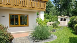 A house with a tiled pathway leading to a wooden door, surrounded by a well-maintained lawn and various plants. - "moseltor" Comfortable Holiday Residence (Monzelfeld)