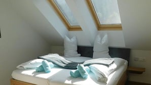 A bedroom with a wooden bed frame, white bedding, and two skylights. - Apartment in Hohentauern Near the ski Area (Hohentauern)