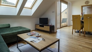 A modern loft apartment with skylights, a green sofa, a wooden coffee table, a TV on a wooden cabinet, and a dining area with yellow chairs. - Apartment in Hohentauern Near the ski Area (Hohentauern)