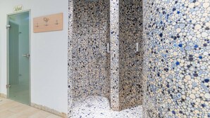 A shower area with a pebble mosaic wall and floor, a wooden door with a sign, and a tiled floor. - Apartment in Hohentauern Near the ski Area (Hohentauern)