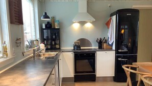 Una cocina compacta con horno integrado, refrigerador y comedor con mesa y sillas de madera.