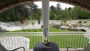 A balcony with a table and chairs, overlooking a landscaped garden with a pond and seating area. - 11 Bohler Brise Modern Retreat (St. Peter-Ording)