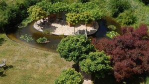 A circular outdoor area with a pond, surrounded by trees and a seating area with chairs and a table. - 11 Bohler Brise Modern Retreat (St. Peter-Ording)