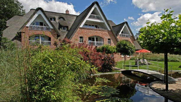 A large, multi-story brick building with a steeply pitched roof and multiple balconies. - 11 Bohler Brise Modern Retreat (St. Peter-Ording)