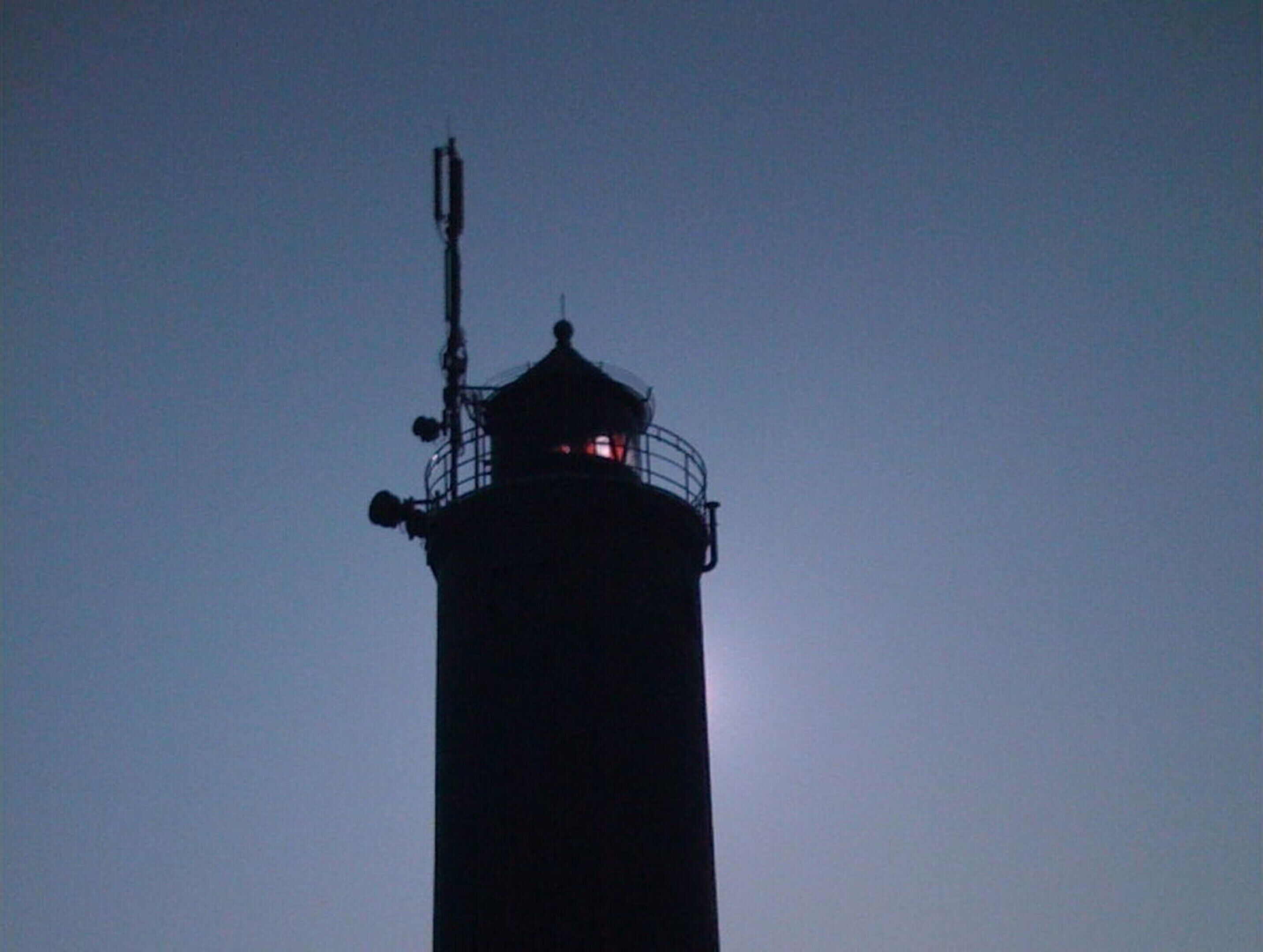 A lighthouse silhouette against a twilight sky.