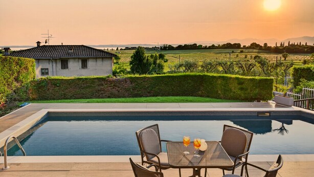 A pool with two chairs and a table, a house in the background, and a clear view of the landscape. - Regarda - Villa Celebrity with private pool and stunning lake view (Lazise)