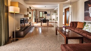 A modern living room with a TV, sofa, coffee table, and dining area. - Regarda - Villa Celebrity with private pool and stunning lake view (Lazise)