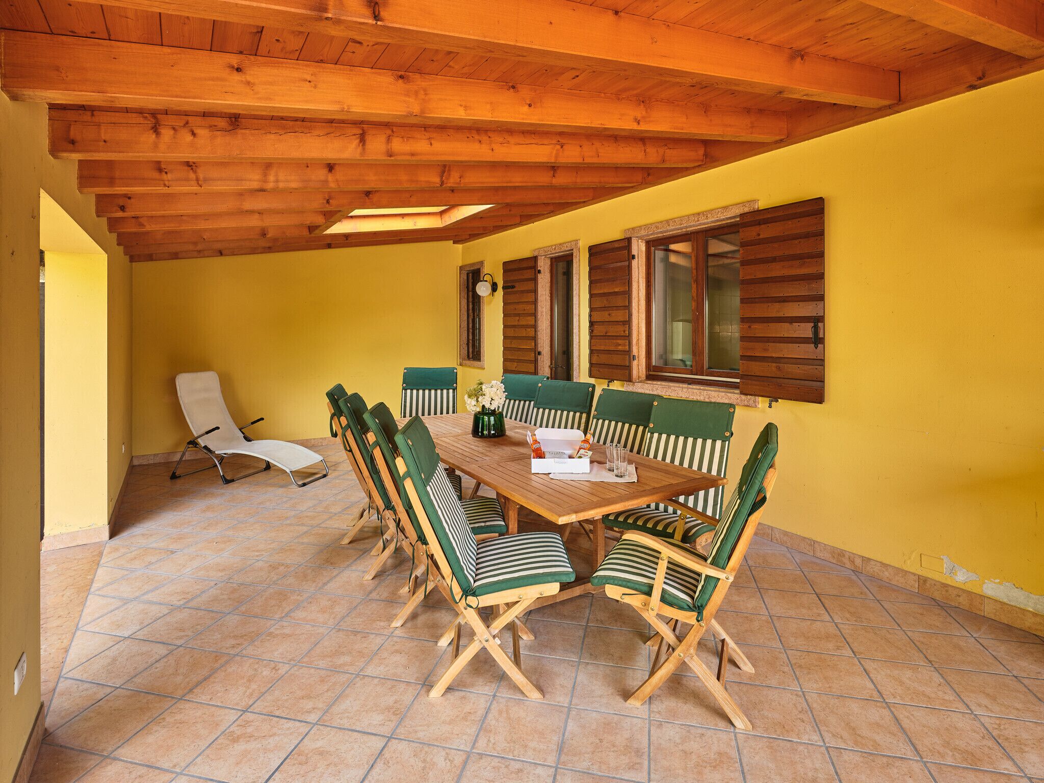 A dining area with a wooden table and chairs, yellow walls, and a tiled floor.