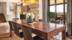 A dining area with a wooden table, chairs, a vase of flowers, and a large hanging lamp. - Regarda - Villa Celebrity with private pool and stunning lake view (Lazise)