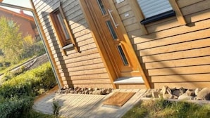 Une maison moderne en bois, dotée d’une porte d’entrée, d’une porte de garage et d’une petite fenêtre.