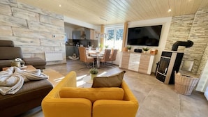 Un salon moderne avec un canapé, un fauteuil jaune et un téléviseur.