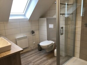 Ein modernes Badezimmer mit Oberlicht, Duschkabine aus Glas und Toilette.