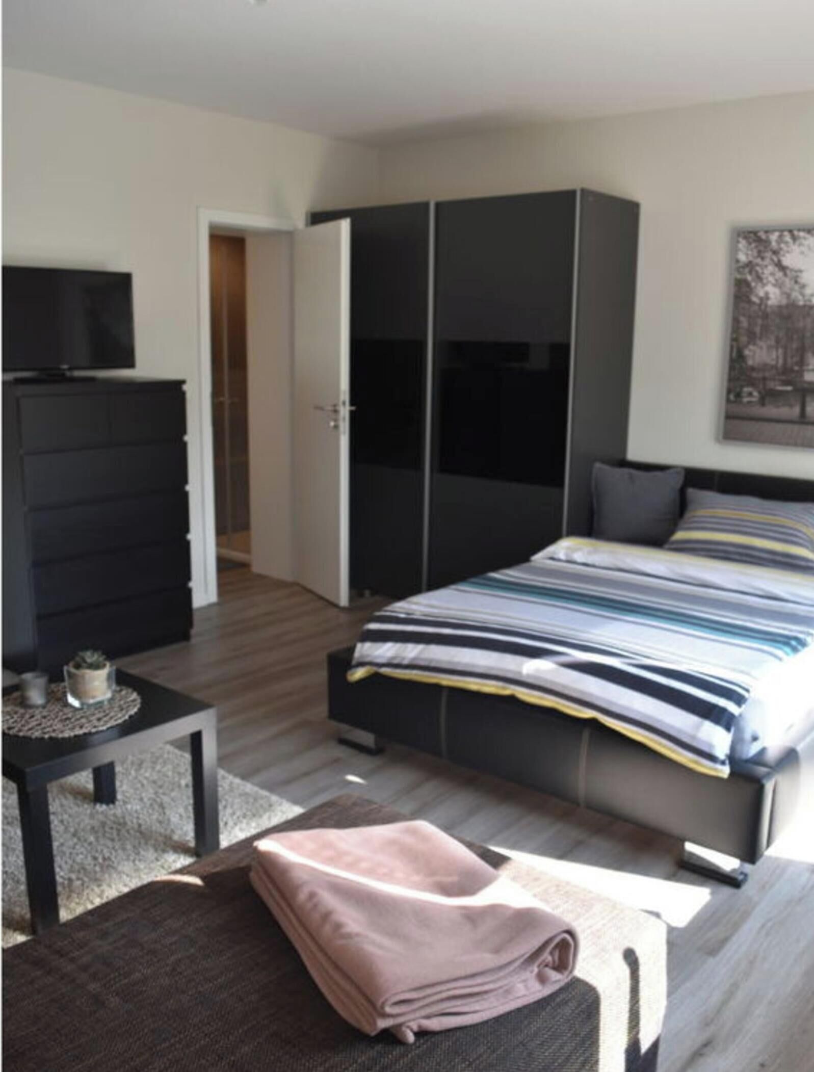 A bedroom with a bed, a dresser, a TV, and a wardrobe.
