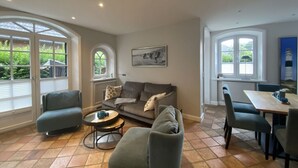 Un salon comprenant un canapé, des fauteuils, une table basse et un coin repas avec une table et des chaises.
