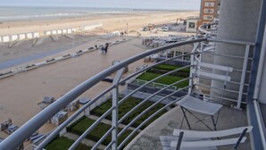 A balcony with a view of a beach and a building in the background.