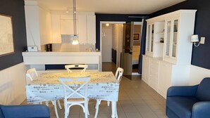 A modern kitchen with white cabinets, a dining table with a polka dot tablecloth, and two blue sofas.