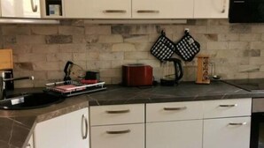 Een keuken met witte kastjes, een zwart aanrecht en een betegelde spatwand.
