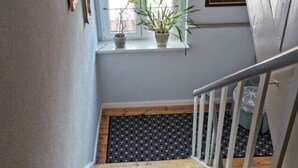 Een houten trap met witte leuningen die uitkomt op een overloop met een raam.