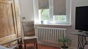Een slaapkamer met een bed, een stoel, een radiator, een raam en een televisie.