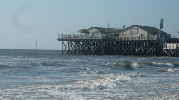 A pier with a building on stilts over the water. - Holiday Apartment Beach View (St. Peter-Ording)