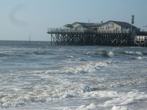 A pier with a building on stilts over the water. - Holiday Apartment Beach View (St. Peter-Ording)
