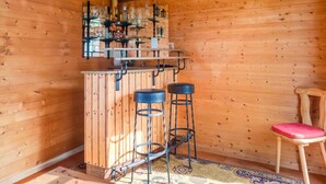 Interior em madeira com área de bar, banquetes e uma cadeira.