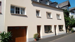 A two-story residential building with a light-colored facade, multiple windows, and a garage. - Philipps Holiday Apartment (Graach)