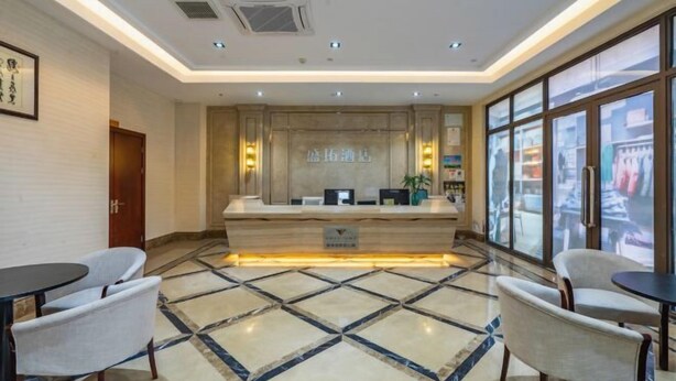 A hotel reception area with a marble floor, reception desk, seating area, and large windows. - Hangzhou Tonglu Shengtuo Serviced Apartment (Tonglu East Station Jiangnan Town) (Tonglu)