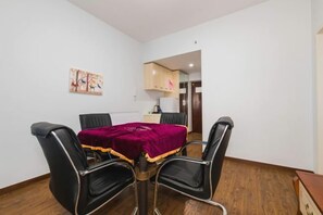Un coin repas avec une table, quatre chaises et une nappe rouge.