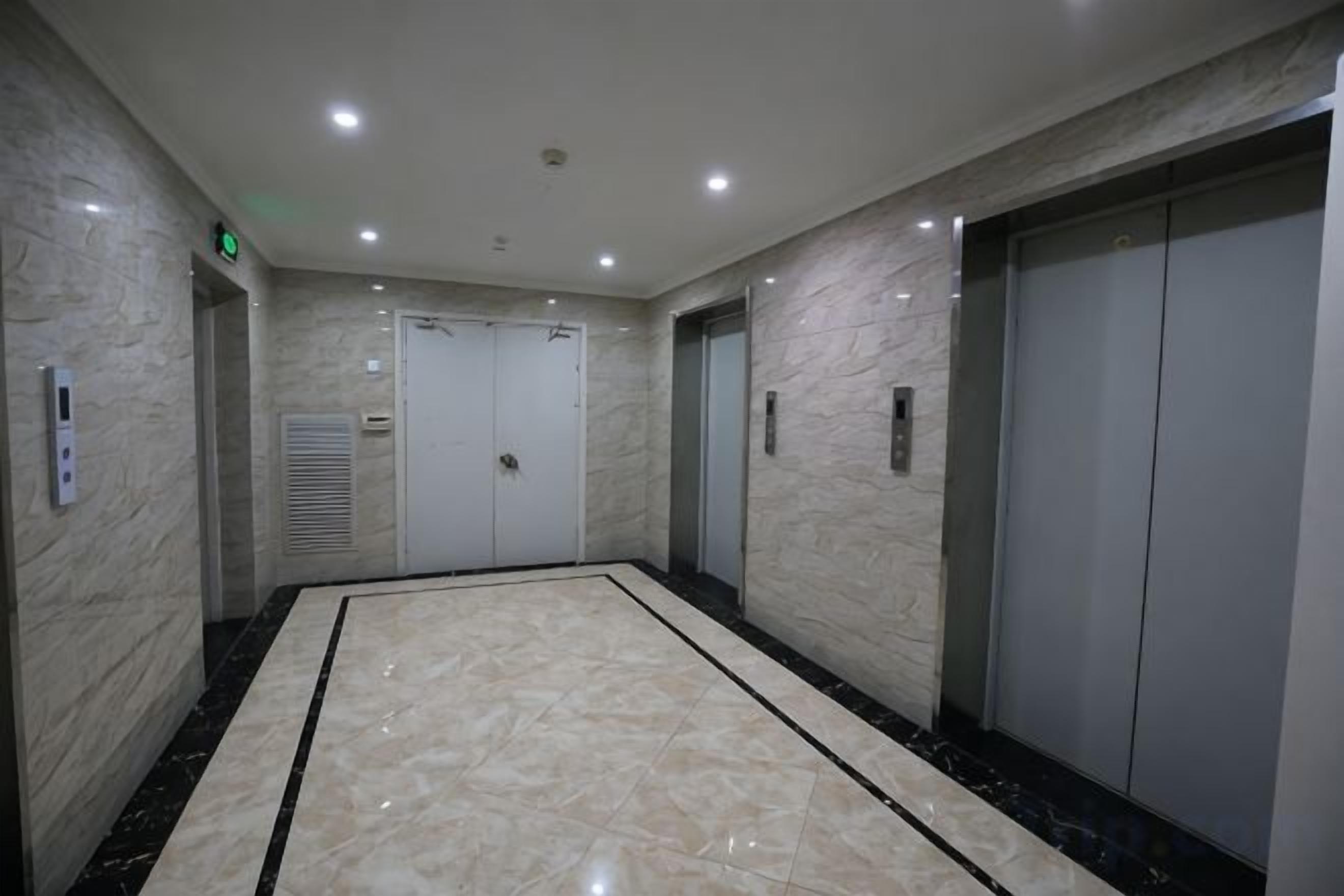 Un  área de ascensor moderna con suelo de mármol, una pared lisa y una puerta de ascensor cerrada.