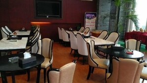 A restaurant with multiple tables and chairs, a television mounted on the wall, and a menu stand. - Hangzhou Tonglu Shengtuo Serviced Apartment (Tonglu East Station Jiangnan Town) (Tonglu)