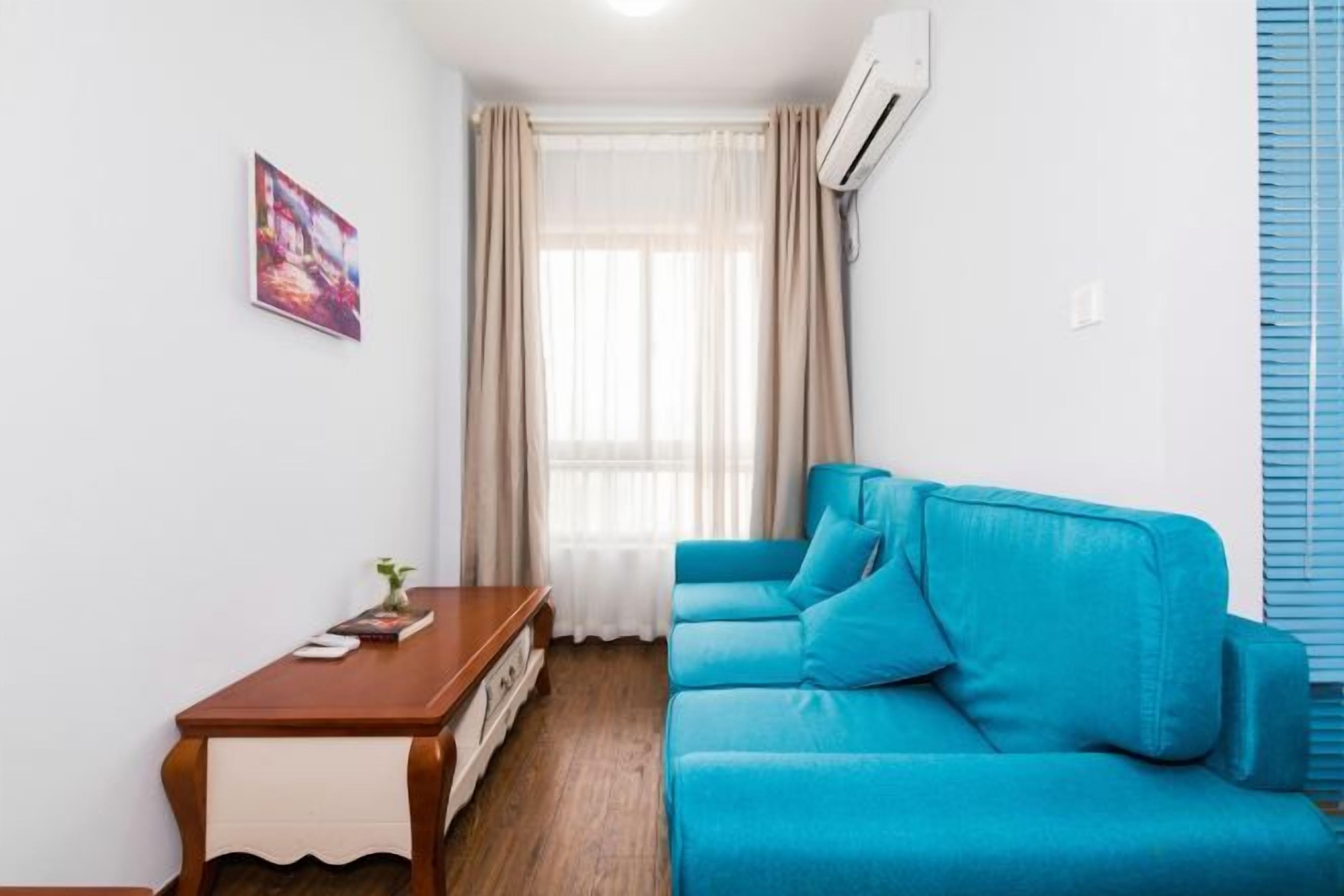 A room with a blue sofa, a wooden table, and a window with curtains.